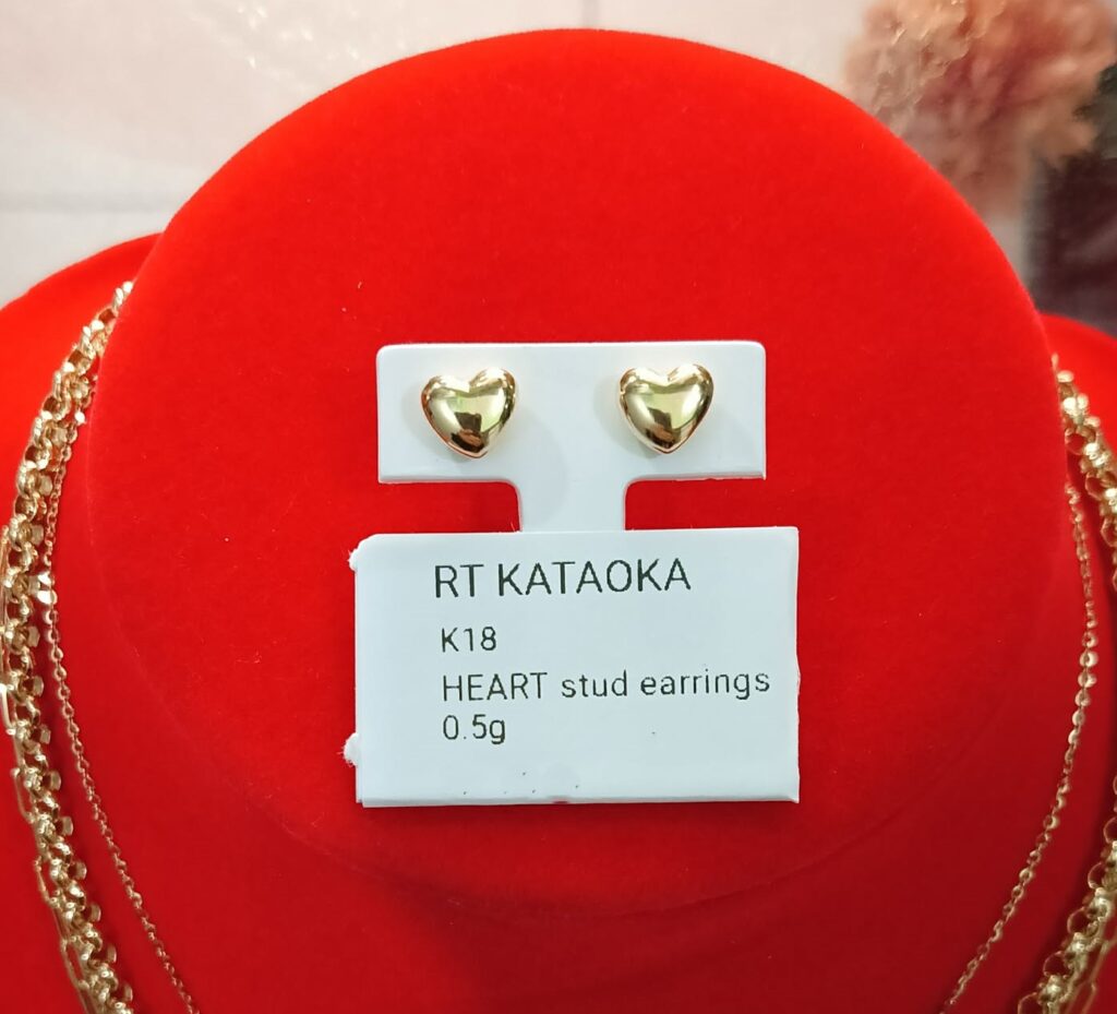 K18 solid Japan gold heart-shaped earrings with a thick hardware-style design on a red display.